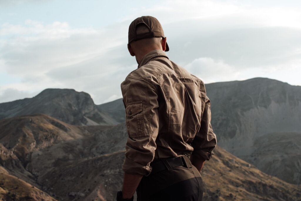 A man stands overlooking a rugged mountain landscape, highlighting adventure and exploration.